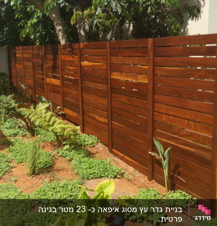 גדר עץ חומה עם צמחים ירוקים בגינה